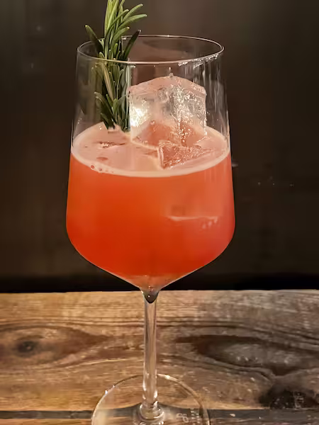 White Wine Glass Filled Withred Liquid Rosemary As A Garnish Cocktail Name Sicilian Love